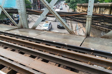 Railways on Long Bien ancient metal bridge with street traffic on background