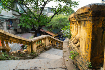 Fototapeta premium Old open outer stone staircase, steps of the old staircase with traces of weathering and destruction. Aged footpath in Hanoi city