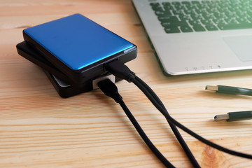 Many Colorful Portable external hard Drives USB3.0 connect to laptop computer on wooden background