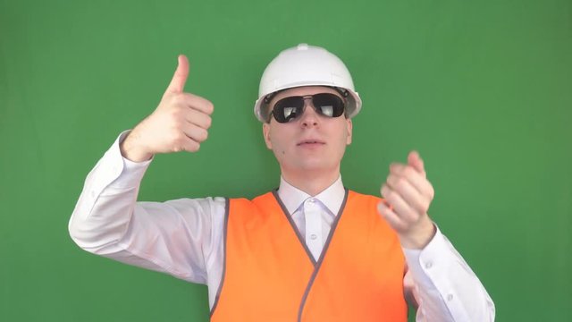 The master boss in black glasses at the workplace gives the command to the crane operator to lift the load up, green background, hromakey, slinger