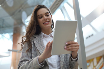 Young smiling businesswoman in office working on digital tablet.