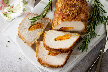 Meat roll (roulade) with with apricot stuffing and spices on a light stone or slate background. Thanksgiving day appetizer. Copy space.
