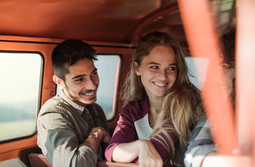 A group of young friends on a roadtrip through countryside, sitting in a minivan.