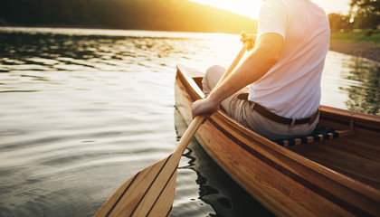 Canoeing. Close up of man holding canoe paddle at sunset lake