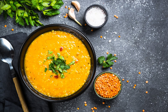 Red lentil soup on black top view.