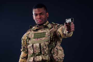 american man in camouflage suit aiming with a pistol