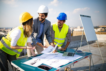 Team of architects and engineer in group on construciton site check documents and business workflow