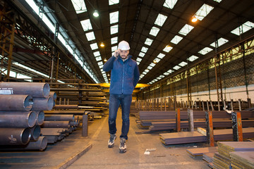 Fototapeta premium male supervisor with clipboard talking on mobile phone in industry