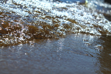 Sea wet pebbles. Small stones lie on the sand. Small waves, close-up.