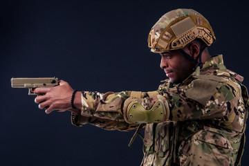 american man in camouflage suit aiming with a pistol