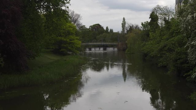 Leamington Spa, tranquil river Leam with ornate bridge and flowing wear on an overcast day