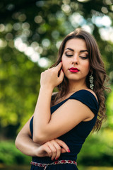 Close up portrait of woman with evening makeup. Woman close her eyes and show fahion slyle. Backgrounf of blue and green bokeh