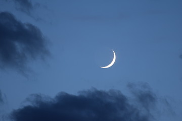 Obraz na płótnie Canvas The new moon on the blue sky in the clouds.