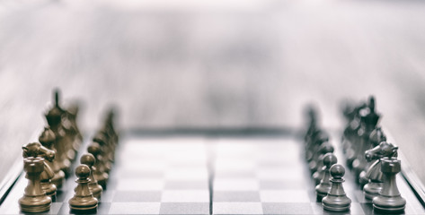 Closeup image of a silver and golden color chess set on chessboard