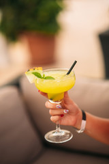 Coctail in woman's hand on the beach. Yellow coctail with melon