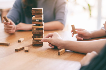 Obraz premium Closeup image of three friends sitting and playing Tumble tower wooden block game together