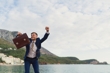 Happy businessman dancing on the beach