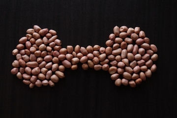 set of raw peanuts making design on a dark wooden table