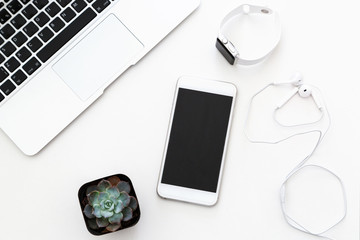 Desktop items: laptop, succulent, notebook, headphones, mobile phone, watch lying on white background. Flat lay, top view, overhead, business concept - Powered by Adobe
