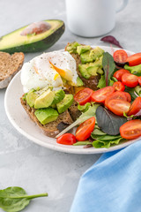Healthy Breakfast with avocado toasts, poached egg and salad