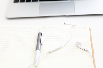 Desktop items: laptop, notebook, headphones lying on white background. Education time, business concept