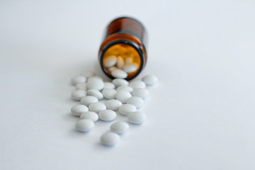 White round pills from yellow glass bottle. On white background. 