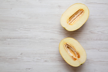 Two halves of melon on a white wooden surface, overhead view. From above, top view. Copy space.