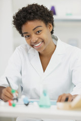 Fototapeta na wymiar smiling chemist wearing coat sitting in lab