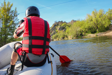 Back view of a hand with red paddle rafting on the river, concept of spring water sports. Selective...