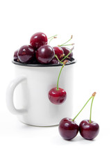 White cup with red sweet cherry isolated on a white background..