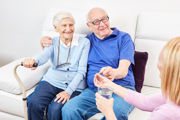 Pflegedienst Frau gibt einem Senior eine Tablette