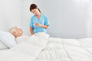 Krankenschwester beim Fieber messen einer Seniorin