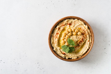 Hummus dip with chickpea, and parsley in wooden plate on white background