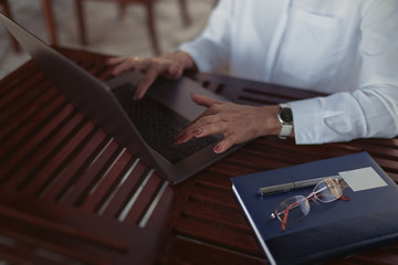 Senior woman typing text on a laptop computer in a cafe. Сlose up 