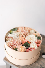 Cute little floral arrangement of mixed flowers on wooden table. Round box. The work of the florist at a flower shop. Delicate Pastel color. Fresh cut flower.
