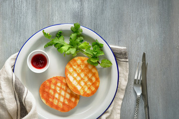 Grilled round slices of Greek cheese with honey, fresh mint and coriander leaves. Flat lay on dark grey wood