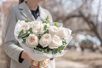 Obraz na płótnie Canvas Mono bouquet of garden roses. Delicate bouquet of mixed flowers in womans hands. the work of the florist at a flower shop. Delicate Pastel color. Fresh cut flower.