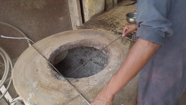 Slow-motion of baking Indian Tandoori Roti, made of wheat flour and/ or maida, sticking the flattened dough to the inside wall of Tandoor, a traditional cylindrical metal oven, handheld stabilized 4k
