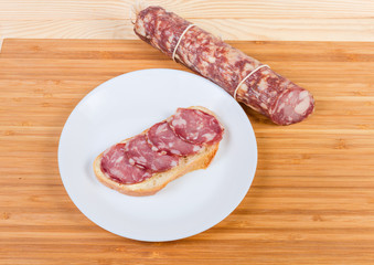 Open sandwich with dry-cured sausage and not sliced sausage