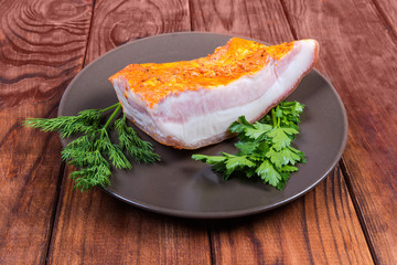 Pice of boiled smoked pork belly on dish with greens
