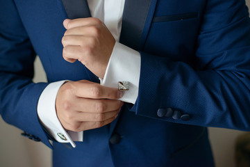 Close-up shot of hands of young white Caucasian male in black tie, fixing his sleeve, sign of sprezzatura and elegance. Groom, or sophisticated businessman, or millennial male model getting ready. 