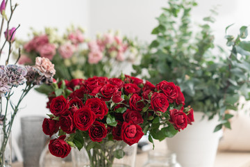 flower shop concept. Vases with different flowers on wooden table. Wallpaper