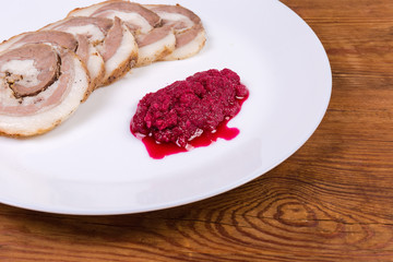 Baked roll of pork belly with horseradish sauce, fragment closeup