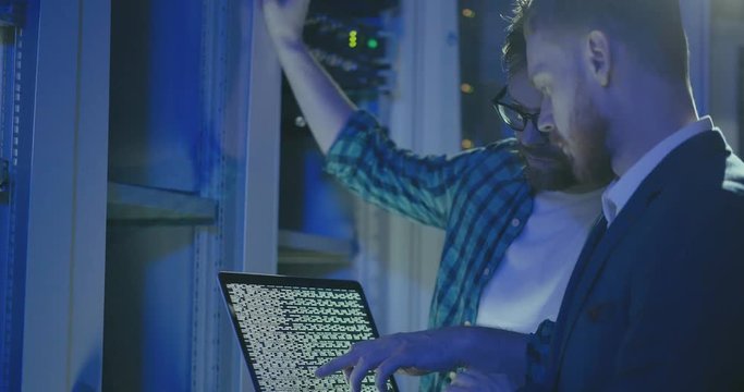 Side view of professional male technicians communicating about code