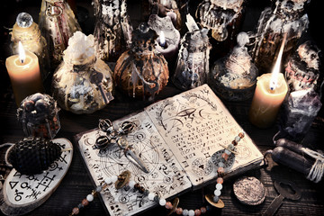 Open magic book with ancient symbols, witch bottles and black candles.
