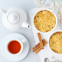 Apple crumble with streusel. Morning breakfast with tea on a light gray table. Top view, close up