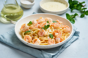 Pasta spaghetti with grilled shrimps, bechamel sauce, mint leaf on blue table, italian cuisine, side view