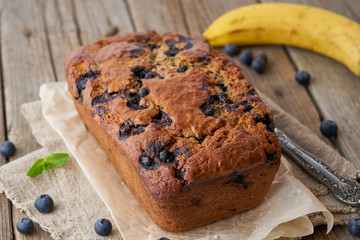 Banana bread on old dark wooden rustic table, slice of cake with banana, close up