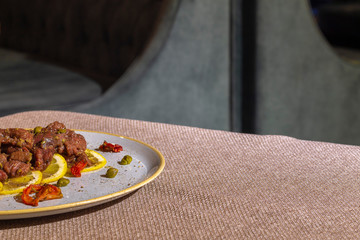 beef tartare with lemon and knife on table near by