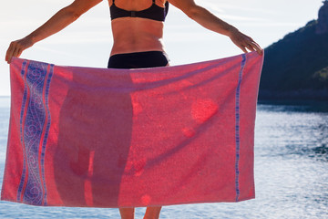 Woman on beach covering hips with towel